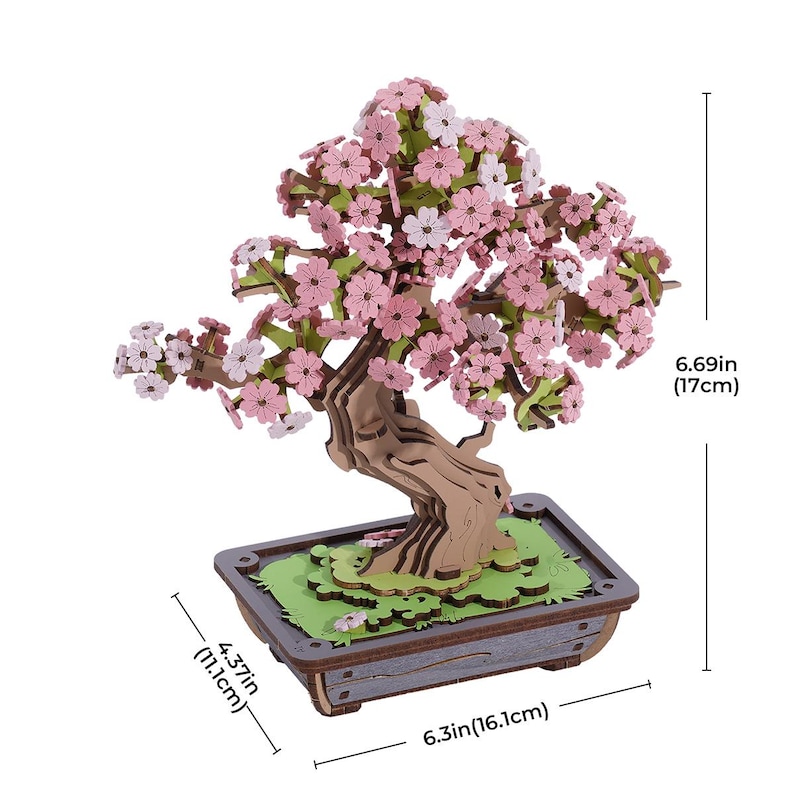 May include: A wooden 3D model of a cherry blossom bonsai tree with pink flowers. The tree is 6.69 inches tall and 6.3 inches wide. The base of the tree is a wooden pot with a green and brown design.