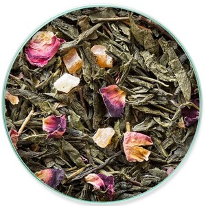 May include: Close-up of loose leaf tea blend with green tea leaves, dried rose petals, and pieces of candied fruit. The tea is presented in a round container with a light green rim. The colors are natural and vibrant, suggesting a high-quality product.