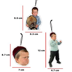 May include: Three different Christmas ornaments featuring a young boy wearing a red hat. The first ornament is 9.5 inches tall and features the boy holding a gold championship belt. The second ornament is 6.3 inches tall and features the boy standing with his arms crossed. The third ornament is 8.7 inches tall and features a close-up of the boy's face.
