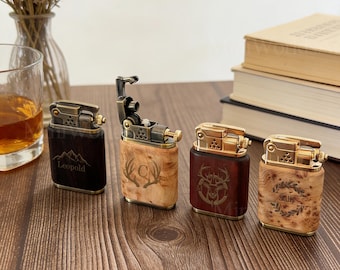 May include: Four decorative lighters with brass accents and wooden bodies. One is open, revealing the internal mechanism. The lighters feature engraved designs and the name "Leopold". The lighters are on a wooden surface.