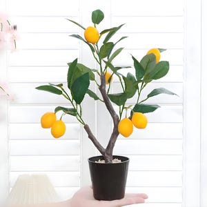 Può includere: Un albero di limone artificiale con foglie verdi e limoni gialli in un vaso nero.