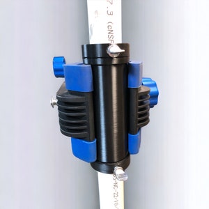 May include: A black pipe clamp with blue plastic handles and a silver knob. The clamp is attached to a white pipe with the text "7.3 (CNSF)" and "OS-NC-22/10" printed on it.