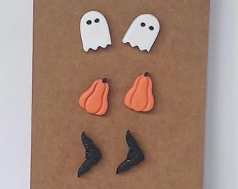 May include: Three pairs of stud earrings on a brown display card labeled Gypsy Clay Cottage. The top pair features white ghosts with black eyes, the middle pair shows orange pumpkins, and the bottom pair consists of black glittery bat shapes.