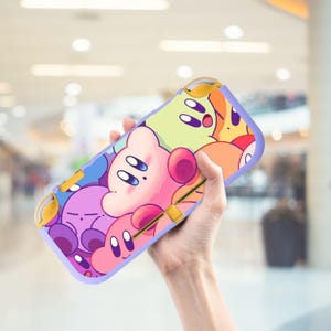 Può includere: Una custodia colorata per Nintendo Switch Lite con un design a cartoni animati. Presenta personaggi in rosa, viola, blu, arancione e giallo. Ha un bordo lilla chiaro e dettagli gialli.