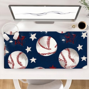May include: A rectangular desk mat featuring a dark blue background with a repeating pattern of white baseballs with red stitching and scattered white and red stars. The mat is positioned on a white desk surface below a computer monitor.