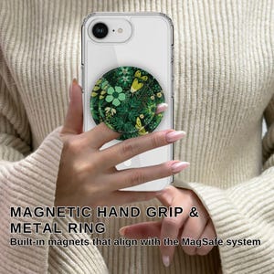 May include: A clear phone case with a green and yellow floral design magnetic hand grip and metal ring. The text "MAGNETIC HAND GRIP & METAL RING" is visible. The phone case is held by a person.