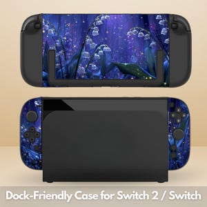 May include: A black gaming console dock and handheld device featuring a decorative skin with a dark blue forest scene, white lily of the valley flowers, and glowing yellow fireflies. The device includes black buttons, joysticks, and a screen.