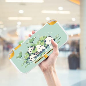 May include: A light green Nintendo Switch Lite case featuring a whimsical illustration of panda bears floating on lily pads. The case has yellow accents and a white border. The design includes green lily pads and water details.