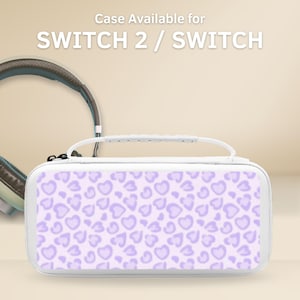 Pode incluir: Um estojo de transporte retangular branco com uma alça superior e um padrão repetitivo de corações roxo-claros na frente. O texto Case Available for SWITCH 2 / SWITCH está impresso em branco acima do estojo, ao lado de um par de auscultadores.