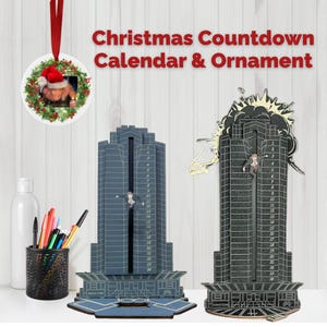 May include: Christmas countdown calendar and ornament. The image shows two skyscraper-shaped countdown calendars, one blue and one black, with a figure descending. A round ornament with a photo and Christmas wreath hangs above. Text reads "Christmas Countdown Calendar & Ornament."