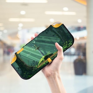 Puede incluir: Una funda negra y verde para consola de juegos con un diseño de bosque y espada. La funda tiene detalles amarillos. La obra de arte muestra una espada en una zona musgosa con árboles y luz solar.