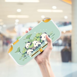 May include: A light green Nintendo Switch Lite case featuring a panda bear design. The case has a white border and yellow accents. The panda bears are depicted in a pond with lily pads. The case is held in a person's hand.