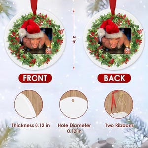 May include: Round Christmas ornament with a photo of a person wearing a Santa hat, surrounded by a green wreath with red berries. The ornament is 3 inches in diameter and has a red ribbon for hanging.