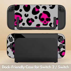 Pode incluir: Uma capa para console de jogos com fundo cinza e um padrão repetitivo de manchas de leopardo pretas e rosa choque, além de crânios estilizados. A capa é exibida em duas vistas, uma encaixada em uma base preta e outra separada do dock.