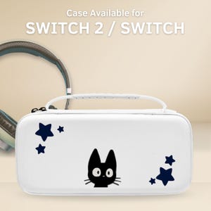 以下が含まれることがあります： Switch 2 / Switch 用の白いキャリングケース。黒い猫の顔と濃い青色の星のグラフィックが特徴です。ケースには白いハンドルがあり、「Case Available for SWITCH 2 / SWITCH」というテキストがあります。背景にはヘッドフォンが見えます。