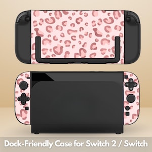 Pode incluir: Uma base e um controle pretos do Nintendo Switch com um design de estampa de leopardo rosa. O texto "Dock-Friendly Case for Switch 2 / Switch" está na parte inferior da imagem.