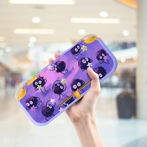 Könnte beinhalten: Eine lila Nintendo Switch Lite Hülle mit einem verspielten Design aus schwarzen, flauschigen Kreaturen mit Sternakzenten. Die Hülle hat einen lavendelfarbenen Hintergrund mit gelben Akzenten und ein schützendes Design.