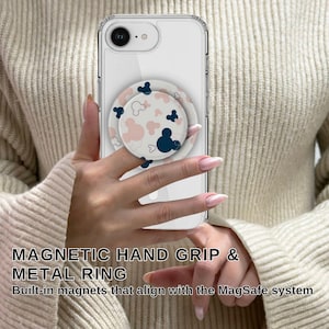 May include: Clear phone case with a pop-up grip featuring a Mickey Mouse design in navy blue and pink. The phone case has a metal ring and is held by a person. The text on the image says "MAGNETIC HAND GRIP & METAL RING".