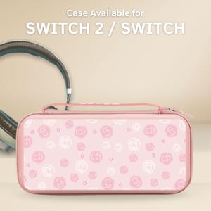 Può includere: Una custodia rosa per Switch 2 / Switch con un motivo floreale a rose. La custodia ha una chiusura a cerniera e un manico. Il testo "Case Available for SWITCH 2 / SWITCH" è in alto.