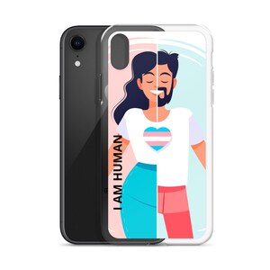 Peut inclure: Une coque de téléphone transparente avec un motif représentant une personne aux cheveux longs et une barbe. La personne porte un t-shirt blanc avec un cœur arc-en-ciel transgenre. Le texte "I AM HUMAN" est sur le côté gauche de la coque.
