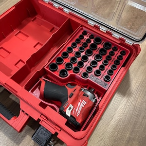 May include: A red Milwaukee tool box with a clear lid. The box contains a Milwaukee impact driver and a variety of sockets.