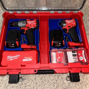 May include: A red Milwaukee tool case with two power tools, a drill and a driver, and a set of drill bits. The case has a blue interior and a black latch.