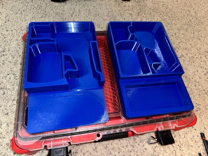 May include: Two blue plastic organizers with compartments for tools or other small items. The organizers are sitting in a red toolbox.