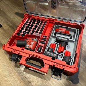 May include: A red tool case containing power tools and accessories. The case is open, showing a set of sockets, a drill, and two batteries. The tools are arranged within a red plastic interior.