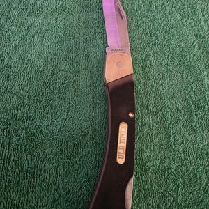 May include: A folding pocket knife with a black handle and a silver blade. The knife has a brass bolster and the text "OLD TIMER" is visible on the handle. The blade is marked "SCHRADE+".