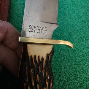 Pu&ograve; includere: Un coltello da caccia della marca Schrade con un manico in corno di cervo marrone e nero e una guardia in ottone. La lama &egrave; stampata con "Schrade U.S.A. 171UH".