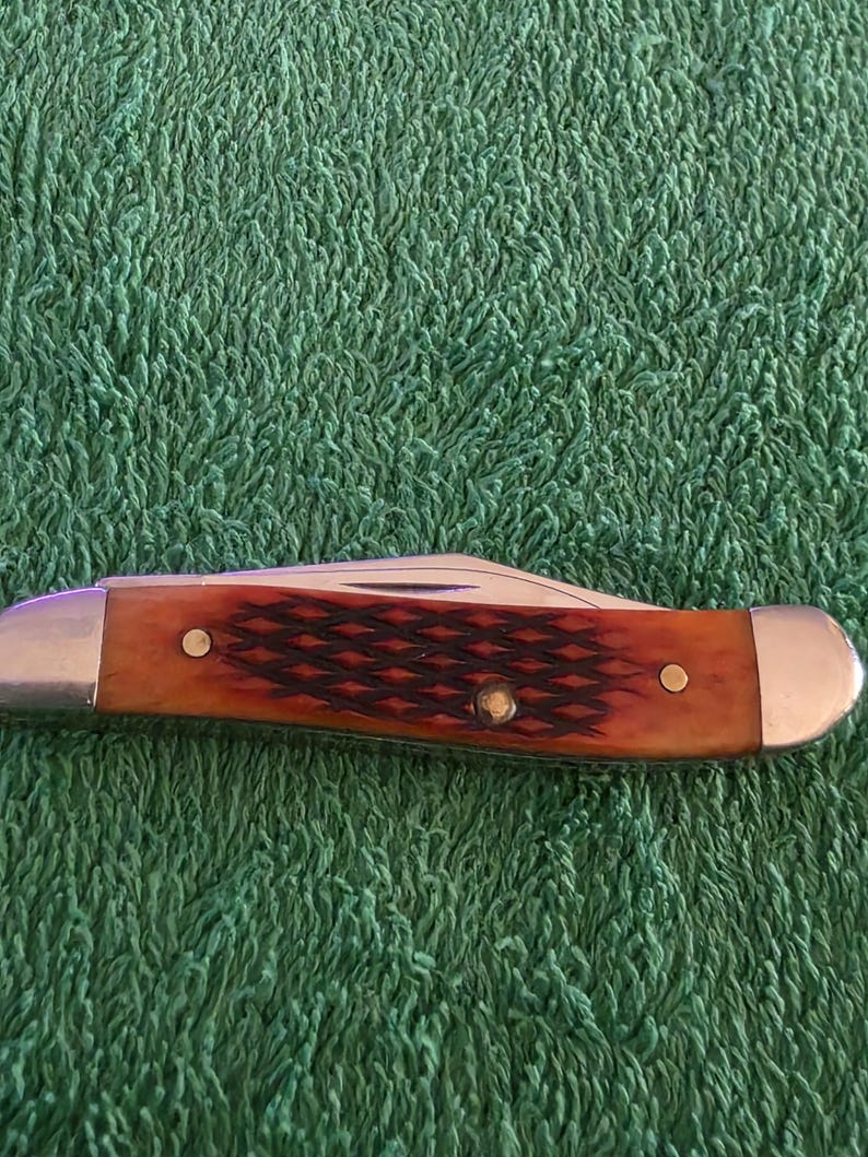 May include: A white ceramic mug with a black handle and the text "But First, Coffee" in a bold, black font. The mug is set against a blurred background, suggesting a cozy setting.