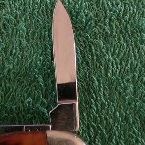 May include: A white ceramic mug with a black handle and the text "But First, Coffee" in a bold, black font. The mug is set against a blurred background, suggesting a cozy setting.