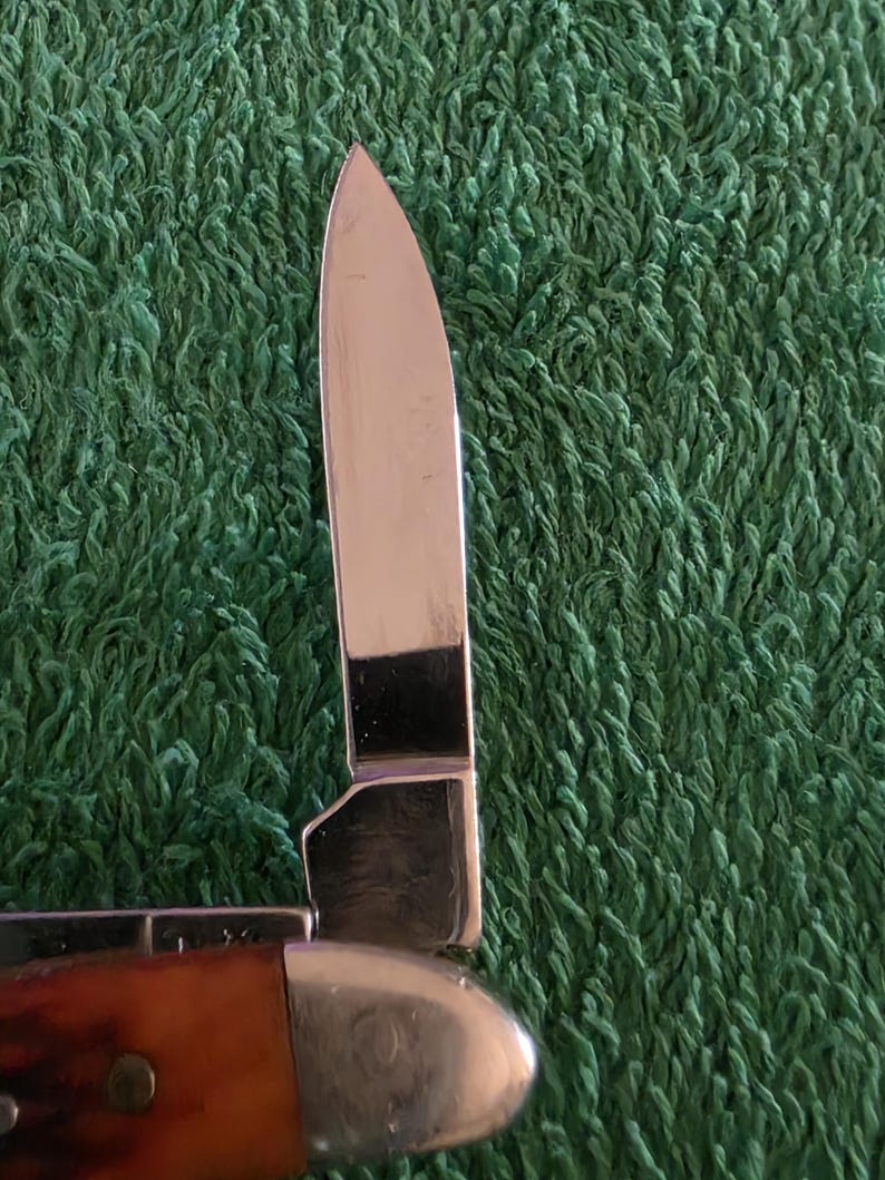 May include: A white ceramic mug with a black handle and the text "But First, Coffee" in a bold, black font. The mug is set against a blurred background, suggesting a cozy setting.