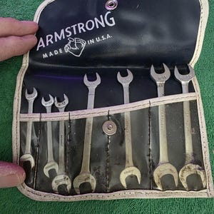 May include: A set of silver wrenches in a black case with the brand name "ARMSTRONG" printed in white. The case is open, revealing the wrenches in individual slots. The text "MADE IN U.S.A." is also visible.