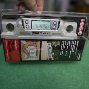 May include: A silver Craftsman digital torpedo level in its original plastic packaging. The device features a backlit LCD screen, two circular bubble vials, and control buttons. The packaging displays the product name, features, and model number 248295.