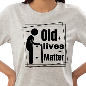 Puede incluir: Una camiseta gris con un gráfico negro de una persona con un bastón y el texto "Old lives matter" en un cuadro negro.