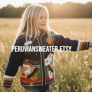May include: A child's navy blue zip-up sweater with colourful embroidered designs. The sweater features a landscape scene with a sun, clouds, and animals. The sleeves have striped cuffs. Text on the sweater reads "PERUVIANSWEATER.ETSY".