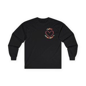 May include: Black long-sleeve shirt with a crew neck. The shirt features a heart-shaped graphic with the words "I LOVE MY RESIDENTS" in a retro font. The heart is outlined in red, with the text in shades of pink, green, and orange.