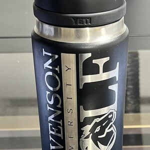 May include: Black insulated water bottle with a handle, featuring the text "STEVENSON UNIVERSITY GOLF" in silver lettering. The bottle has a silver band and the brand name "YETI" is visible.