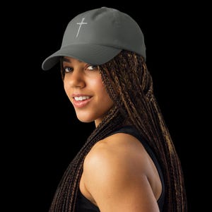 May include: A grey baseball cap featuring a white embroidered sword. The cap has a curved peak and an adjustable strap. The hat is made of a soft, durable material, suitable for everyday wear.