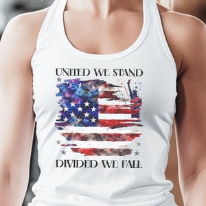 以下が含まれることがあります： 「United We Stand, Divided We Fall」というテキストと、ダメージ加工されたアメリカ国旗のグラフィックがプリントされた白いタンクトップです。