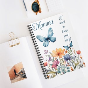 May include: A white spiral bound notebook with a blue butterfly and floral design. The text "Momma I want to know your story!" is printed on the cover.