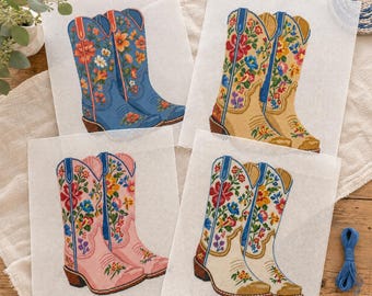 May include: Four square needlepoint canvases featuring pairs of cowboy boots in blue, tan, pink, and cream. Each boot design is decorated with vibrant, multi-colored floral embroidery patterns, including red, yellow, and blue flowers on the shafts.