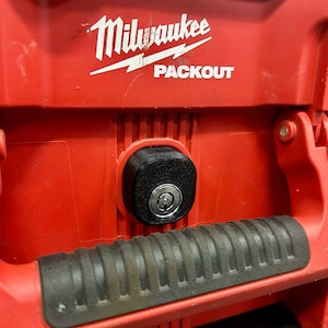 Puede incluir: Caja de herramientas roja Milwaukee Packout con una cerradura negra y una manija de goma negra.