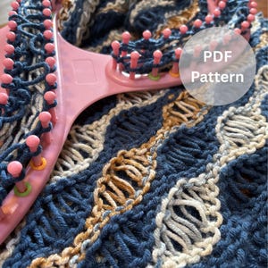 May include: A pink knitting loom with blue yarn in progress, alongside a completed knitted piece in shades of blue, tan, and cream. The text "PDF Pattern" is overlaid on the image, indicating a digital knitting pattern.