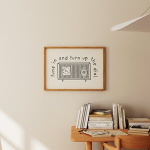 May include: A framed print with a black and white illustration of a vintage radio with the text "tune in and turn up the dial".