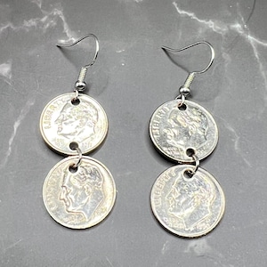 May include: Silver-toned dangle earrings made from US dimes. Each earring features two dimes connected by a small silver loop. The dimes display the profile of a man and the word "LIBERTY".