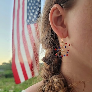 May include: Gold earrings with red, white, and blue beads, shaped like a firework.