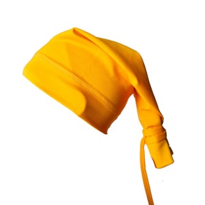 Puede incluir: Un gorro amarillo brillante con una cuerda larga y fina atada. El gorro está hecho de una tela suave y elástica.