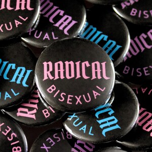 May include: A collection of black buttons with the words "RADICAL BISEXUAL" in pink and "BISEXUAL" and "RADICAL" in blue. The buttons are round and have a glossy finish.